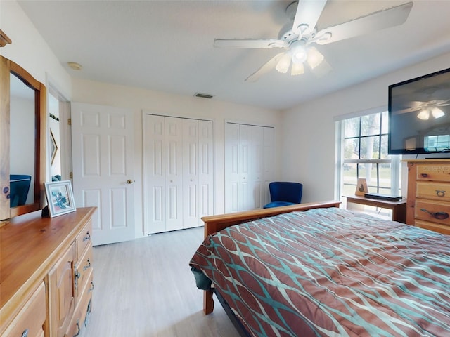 bedroom featuring ceiling fan, light wood-type flooring, and multiple closets