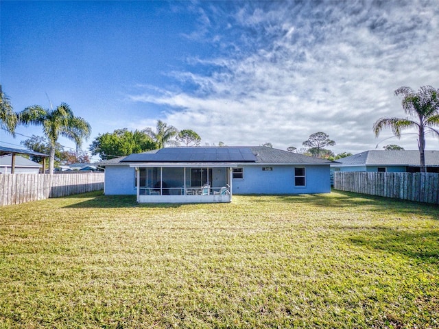 rear view of house featuring a lawn, a sunroom, and solar panels