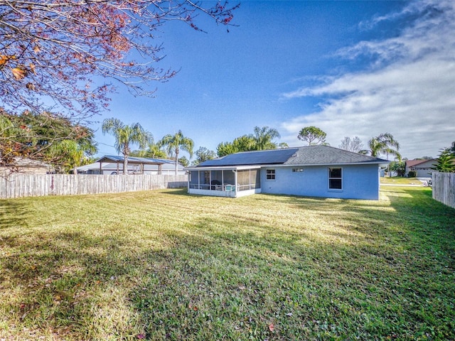 rear view of property with a lawn, solar panels, and a sunroom