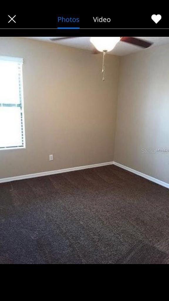 spare room with ceiling fan and dark carpet