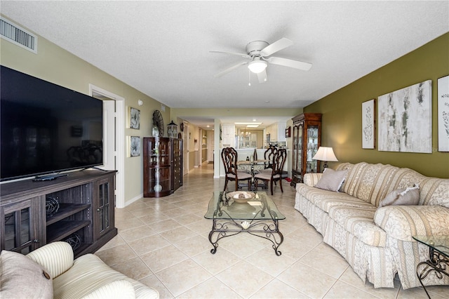 living room with a textured ceiling, light tile patterned flooring, and ceiling fan