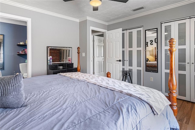 bedroom featuring a textured ceiling, dark wood-type flooring, ceiling fan, crown molding, and multiple closets