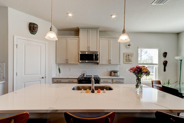 kitchen with a breakfast bar area, light stone countertops, a center island with sink, and pendant lighting