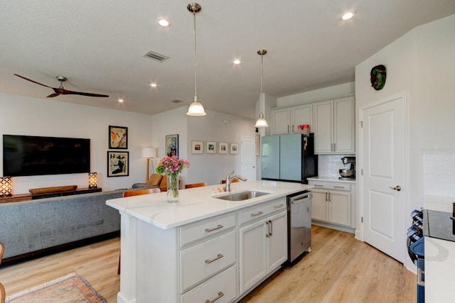 kitchen featuring stainless steel dishwasher, a kitchen island with sink, sink, pendant lighting, and range