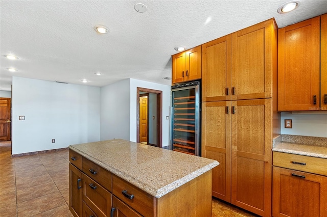 kitchen with a center island, light tile patterned floors, wine cooler, and light stone countertops