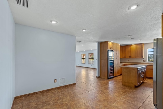 kitchen featuring a kitchen island, a textured ceiling, and stainless steel fridge