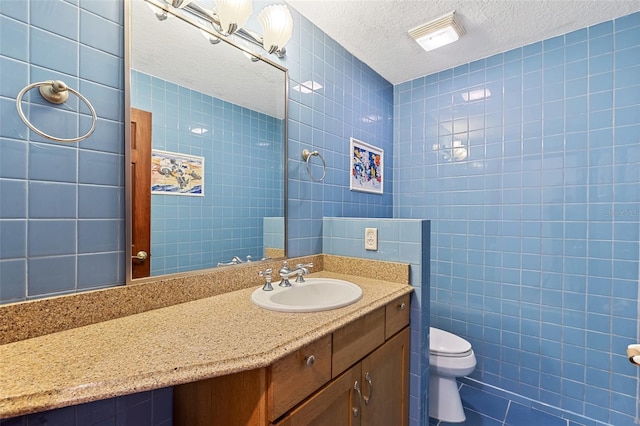 bathroom with tile walls, vanity, a textured ceiling, and toilet