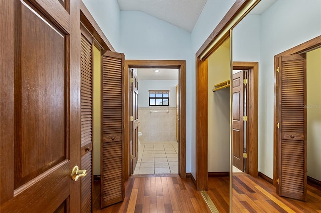 hall with lofted ceiling and hardwood / wood-style floors