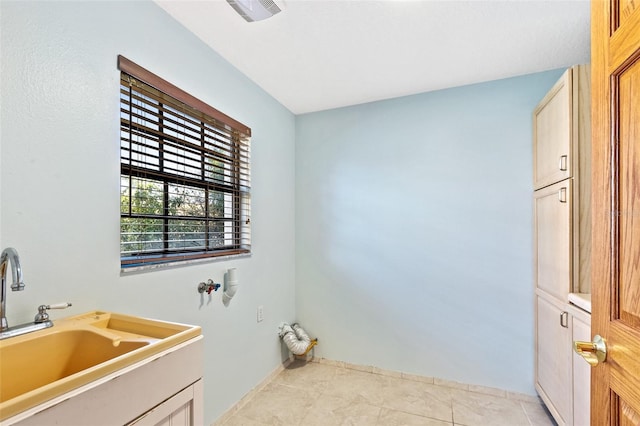 laundry room with cabinets, light tile patterned flooring, and sink