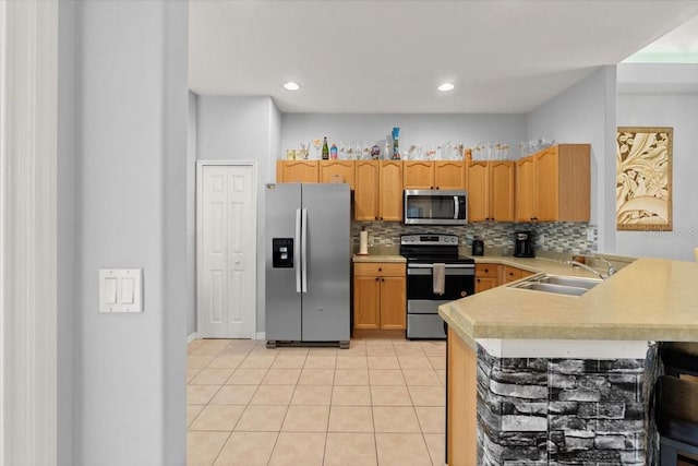 kitchen featuring kitchen peninsula, tasteful backsplash, stainless steel appliances, sink, and light tile patterned floors