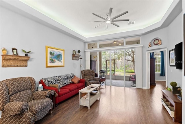 living room featuring a tray ceiling, ceiling fan, and dark hardwood / wood-style flooring