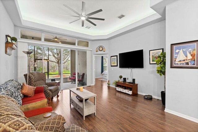 living room featuring dark hardwood / wood-style floors, a raised ceiling, and a towering ceiling