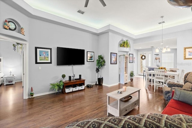 living room with dark wood-type flooring and ceiling fan with notable chandelier