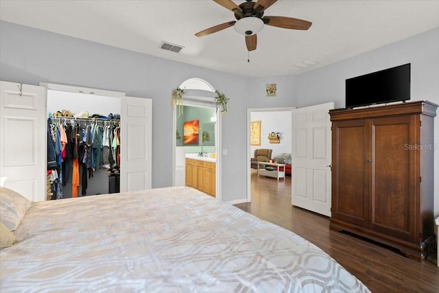 bedroom featuring ceiling fan, dark wood-type flooring, a spacious closet, connected bathroom, and a closet