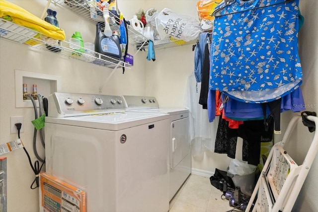 clothes washing area featuring washer and clothes dryer and light tile patterned flooring