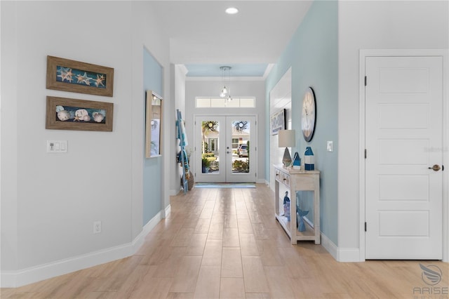 entrance foyer with light hardwood / wood-style floors, french doors, and ornamental molding