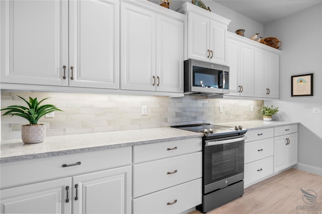 kitchen featuring appliances with stainless steel finishes, white cabinetry, decorative backsplash, and light hardwood / wood-style floors