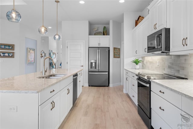 kitchen featuring decorative light fixtures, stainless steel appliances, a center island with sink, white cabinets, and sink