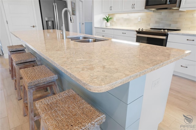 kitchen featuring appliances with stainless steel finishes, a large island with sink, and a kitchen bar