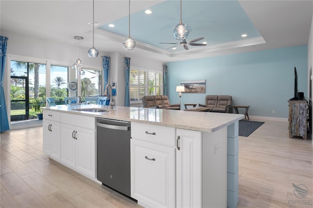 kitchen featuring ceiling fan, an island with sink, dishwasher, and a tray ceiling