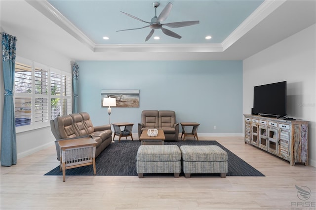 living room featuring ornamental molding, ceiling fan, light hardwood / wood-style flooring, and a tray ceiling