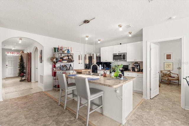 kitchen with sink, a breakfast bar, white cabinetry, an island with sink, and decorative light fixtures