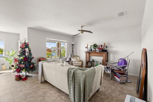 living room with ceiling fan, a textured ceiling, and light tile patterned floors