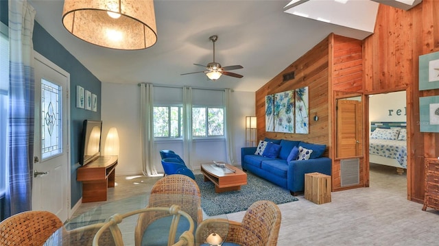 living room featuring ceiling fan, wood walls, and lofted ceiling