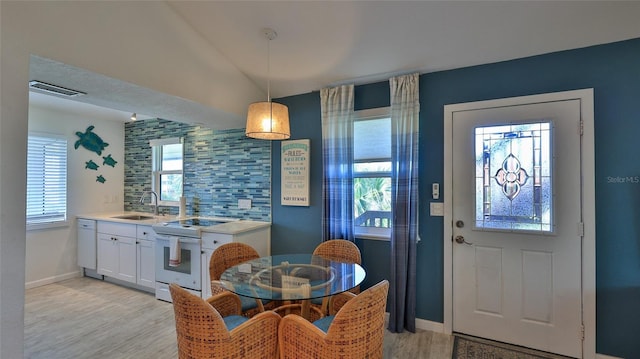 kitchen featuring pendant lighting, white cabinets, white electric range oven, sink, and vaulted ceiling