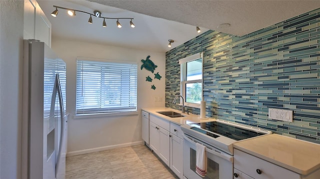 kitchen with sink, white cabinetry, white appliances, and tasteful backsplash