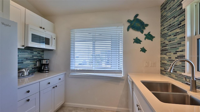 kitchen with tasteful backsplash, white appliances, sink, and white cabinets