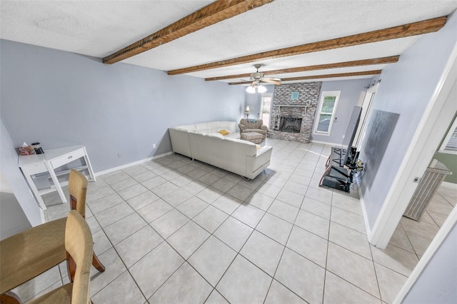 tiled living room with a brick fireplace, a textured ceiling, ceiling fan, and beamed ceiling