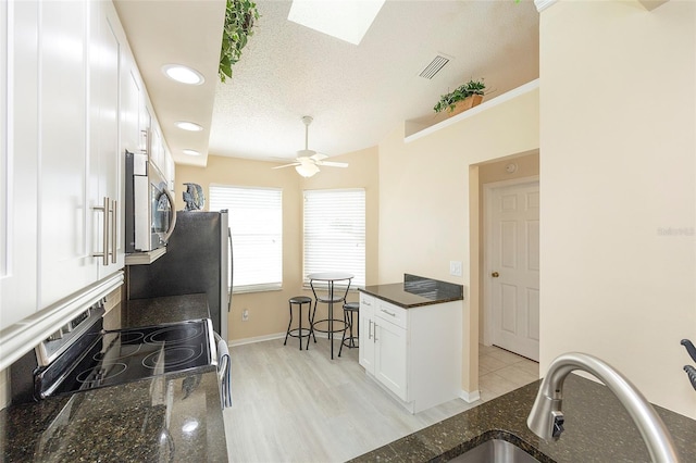 kitchen with dark stone countertops, appliances with stainless steel finishes, ceiling fan, sink, and white cabinetry