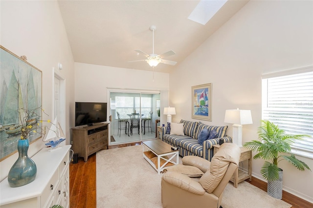 living room with dark wood-type flooring, high vaulted ceiling, ceiling fan, and a skylight