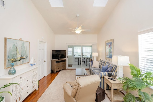 living room with high vaulted ceiling, dark hardwood / wood-style flooring, a skylight, and ceiling fan