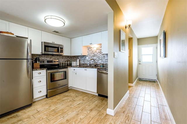 kitchen featuring white cabinets, appliances with stainless steel finishes, light hardwood / wood-style floors, and tasteful backsplash