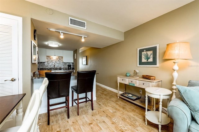 kitchen featuring white cabinets, light hardwood / wood-style flooring, sink, and decorative backsplash