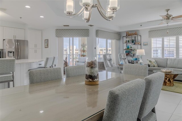 tiled dining room with ceiling fan with notable chandelier and a wealth of natural light