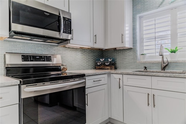 kitchen featuring sink, appliances with stainless steel finishes, light stone countertops, white cabinets, and decorative backsplash