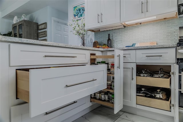 interior details featuring white cabinets, light stone countertops, and backsplash