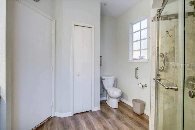 bathroom with walk in shower, toilet, and hardwood / wood-style floors