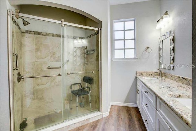 bathroom with walk in shower, vanity, and hardwood / wood-style floors