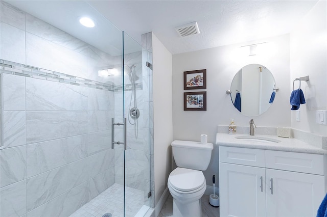 bathroom featuring toilet, vanity, a textured ceiling, and a shower with shower door