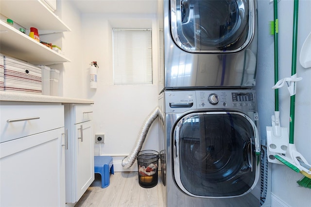 laundry room featuring stacked washer / drying machine and light hardwood / wood-style floors