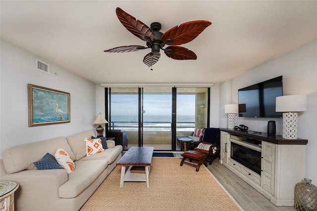 living room with light wood-type flooring, ceiling fan, and expansive windows