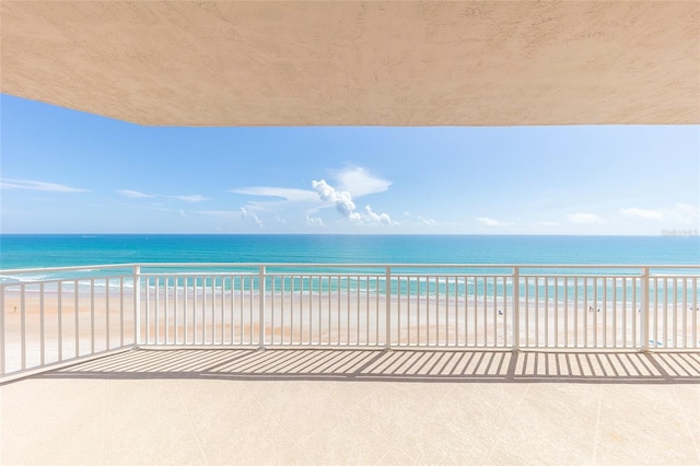 balcony featuring a view of the beach and a water view