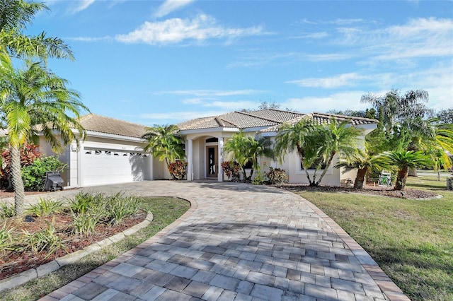 mediterranean / spanish home featuring a garage and a front lawn