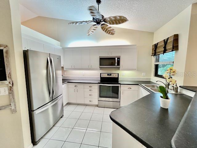 kitchen featuring lofted ceiling, stainless steel appliances, and white cabinetry