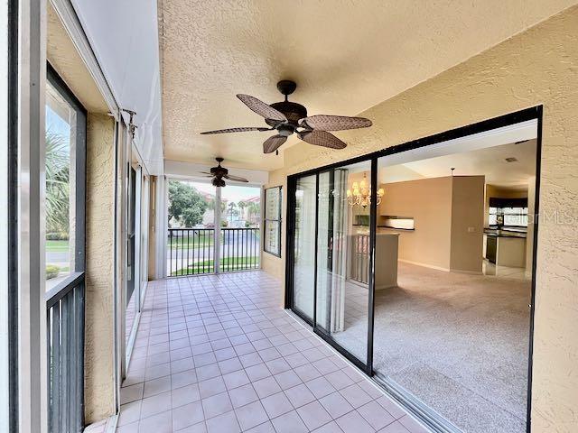 unfurnished sunroom with ceiling fan with notable chandelier and plenty of natural light