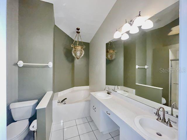 bathroom with tile patterned floors, a bath, toilet, and vanity